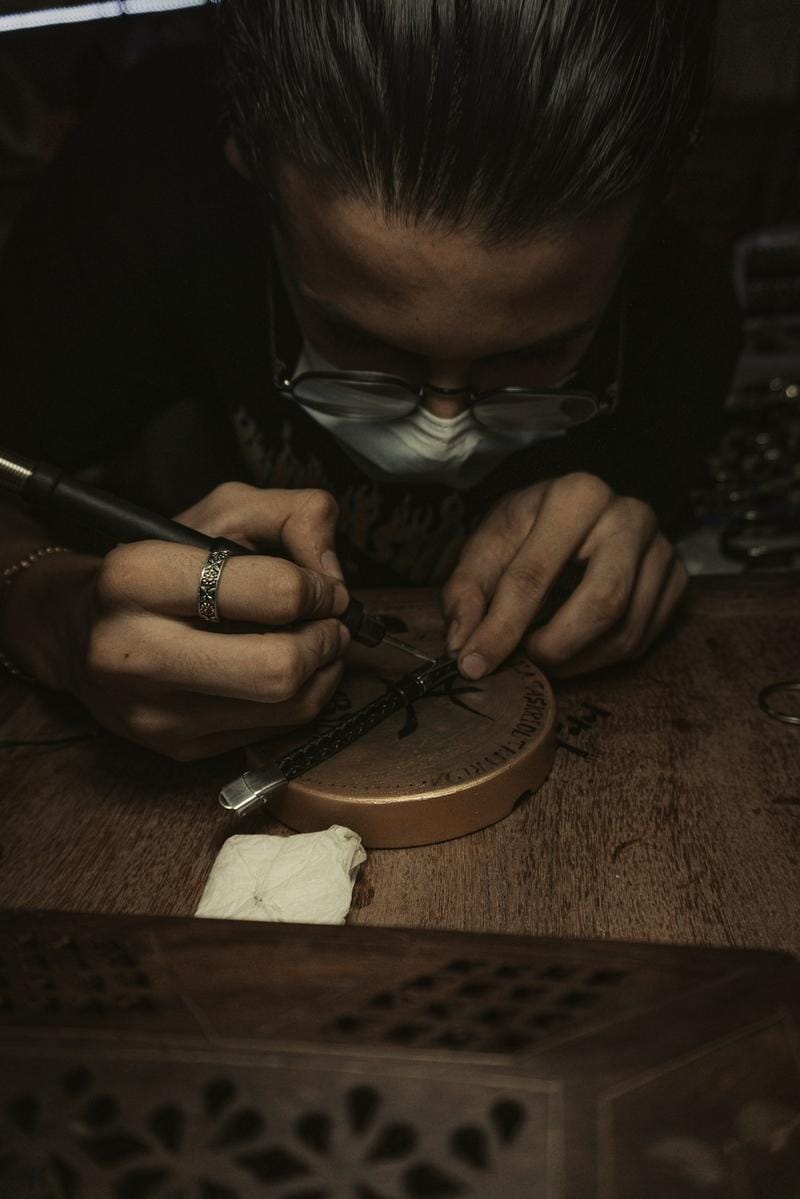 artisanal jewelry making Close-up of a handcrafted jewelry artisan working meticulously on a silver ring in a well-lit studio with tools spread around