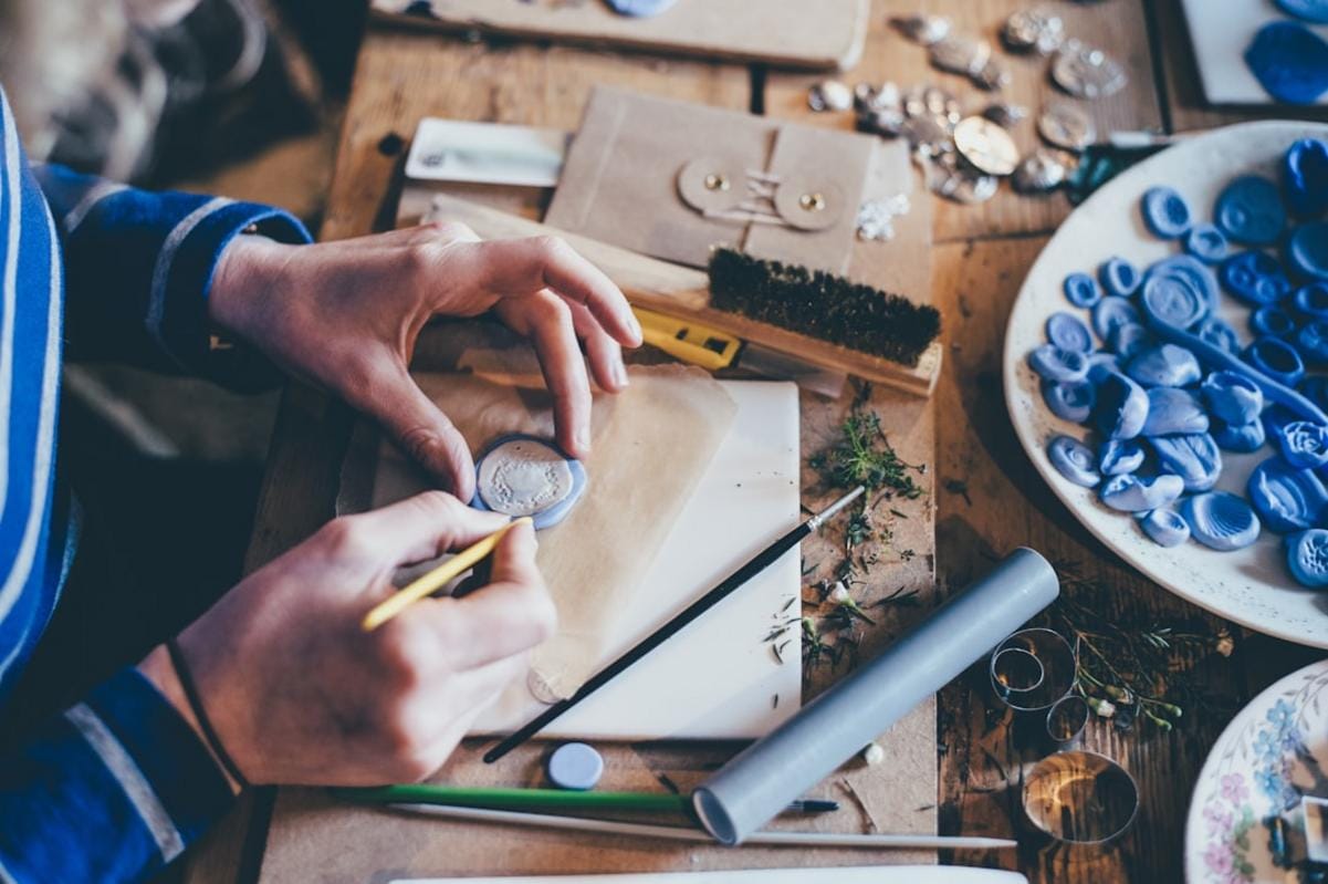 An artisan working on a silver ring in a sunlit studio, emphasizing craftsmanship and dedication.