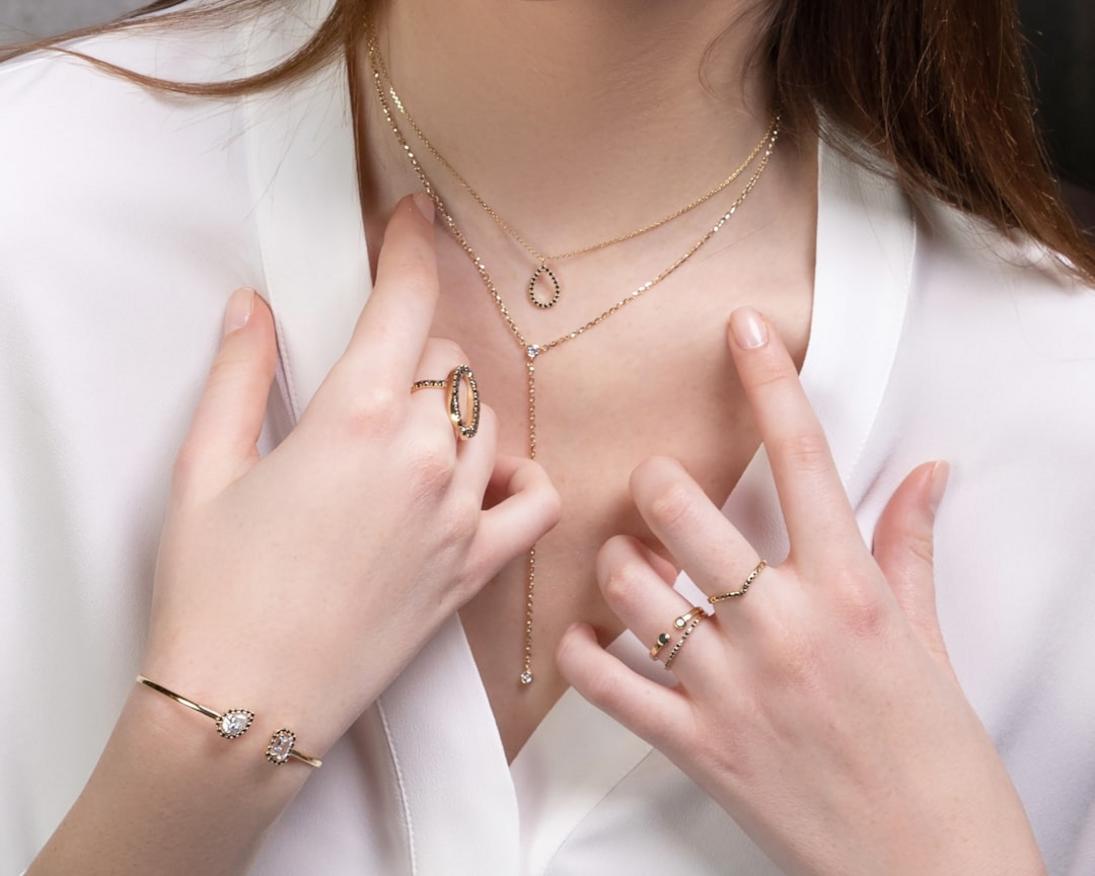 artisanal jewelry styling A model wearing layered artisanal jewelry including necklaces, rings, and earrings styled with casual and formal outfits, illustrating versatile accessorizing.